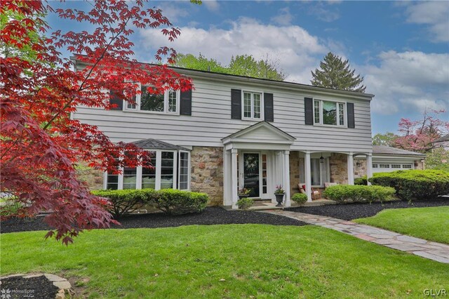 colonial inspired home featuring a front yard and a garage