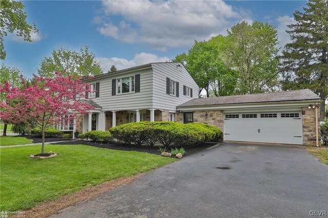 colonial home featuring a garage and a front lawn