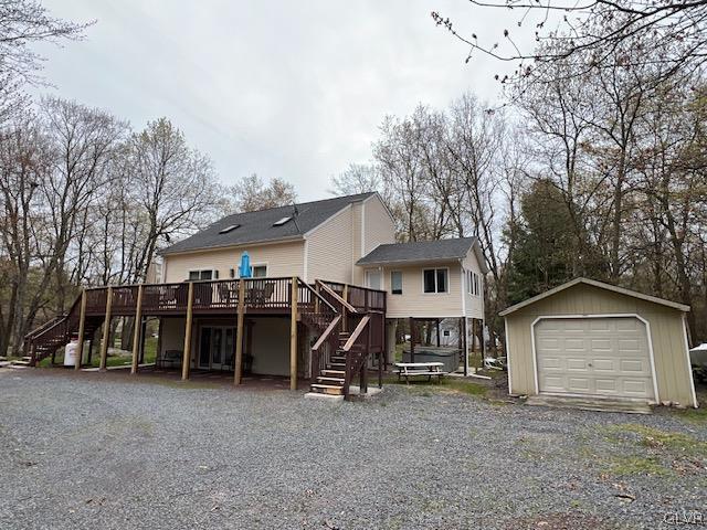 rear view of house featuring a wooden deck, an outdoor structure, and a garage