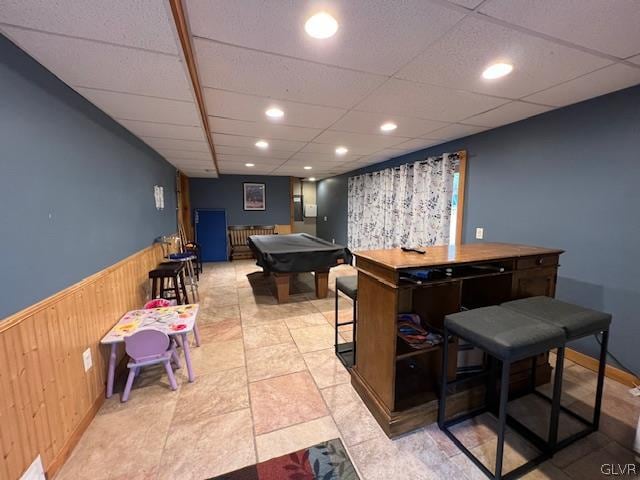 game room featuring a drop ceiling, indoor bar, pool table, and wood walls