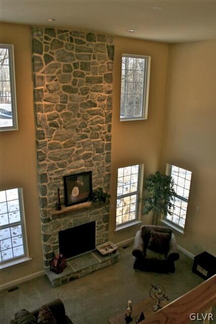 carpeted living room with a towering ceiling, a wealth of natural light, and a fireplace