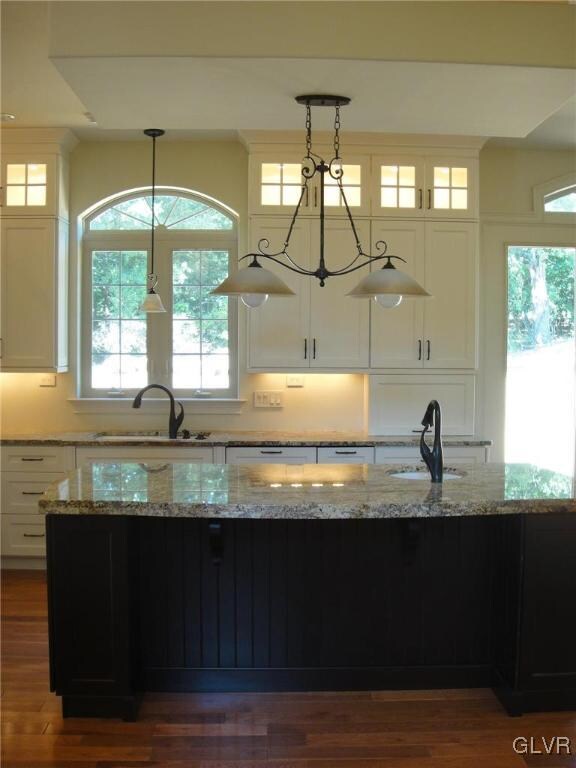 kitchen featuring light stone countertops, sink, hanging light fixtures, and white cabinets