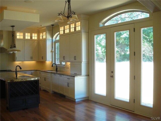 kitchen with light stone counters, sink, hanging light fixtures, and white cabinets