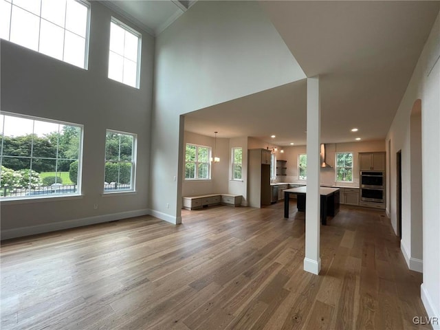 unfurnished living room with hardwood / wood-style floors, a high ceiling, and a notable chandelier