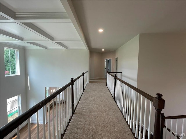 hall with light colored carpet and beamed ceiling