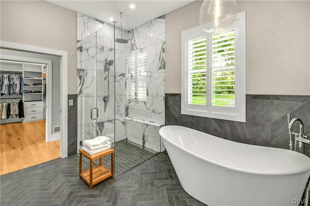 bathroom with shower with separate bathtub, tile walls, and tile patterned floors