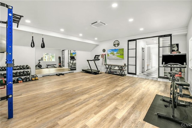 exercise room featuring lofted ceiling and light wood-type flooring