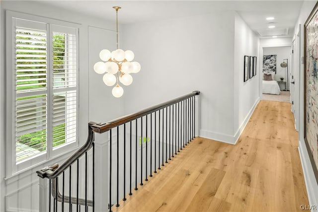 hall featuring an inviting chandelier and light wood-type flooring