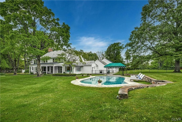 back of property with a fenced in pool and a yard