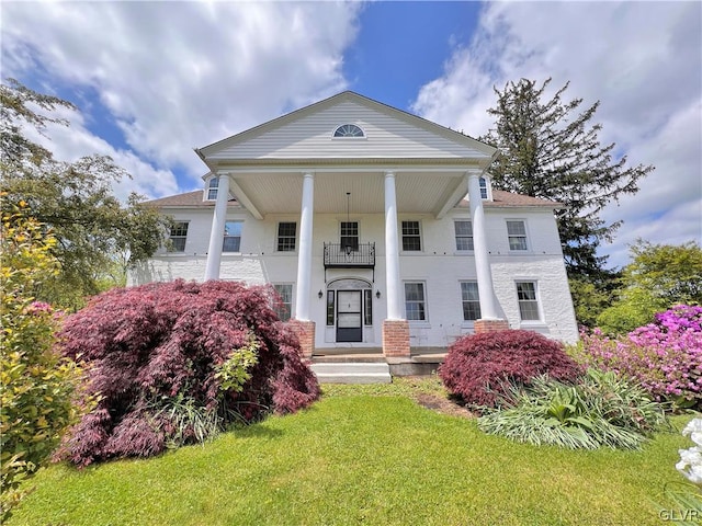 neoclassical home with a balcony and a front lawn