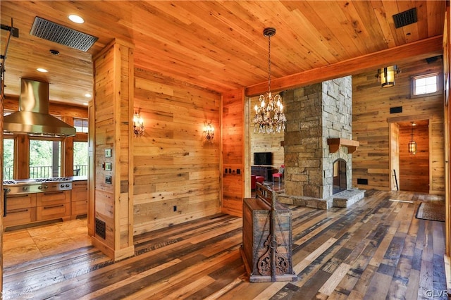 interior space with hardwood / wood-style flooring, wooden walls, wood ceiling, and a stone fireplace