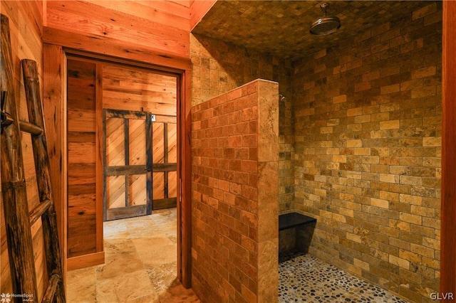 bathroom with tile patterned flooring, walk in shower, and brick wall