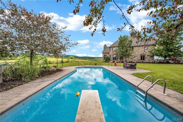 outdoor pool with a diving board, a patio, and a yard