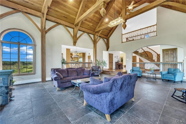 living room with arched walkways, vaulted ceiling with beams, stairway, wood ceiling, and baseboards