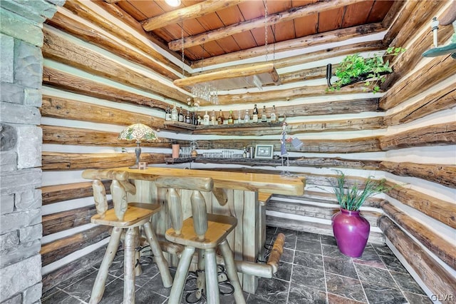 interior space featuring stone finish flooring, beamed ceiling, wooden ceiling, and wet bar