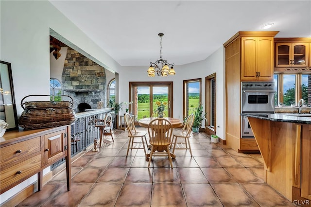 dining space featuring an inviting chandelier, light tile patterned floors, and a fireplace