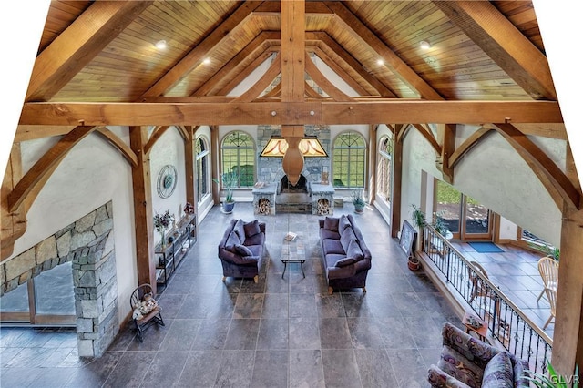 unfurnished living room featuring wood ceiling, high vaulted ceiling, beamed ceiling, and a stone fireplace