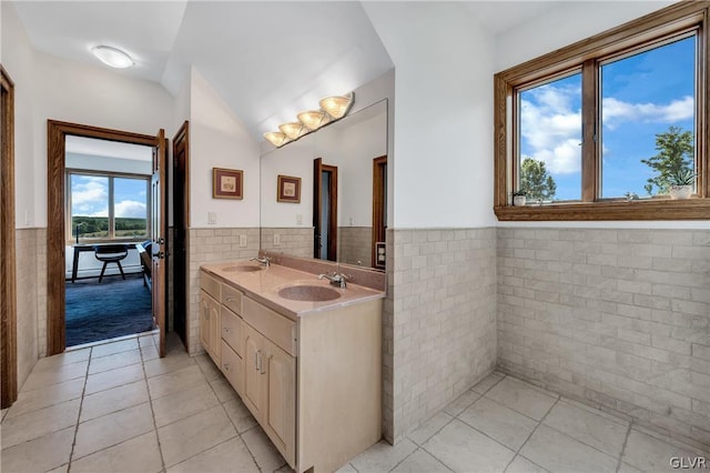 full bath featuring tile patterned flooring, wainscoting, a sink, and tile walls