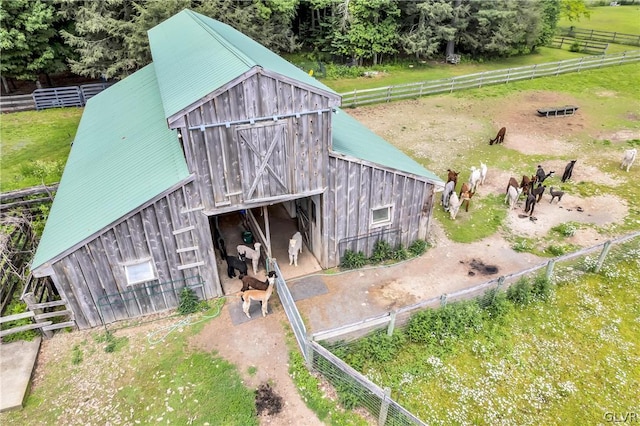 view of barn featuring fence and a lawn