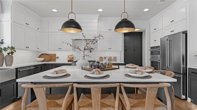 kitchen featuring stainless steel appliances, white cabinetry, and hanging light fixtures