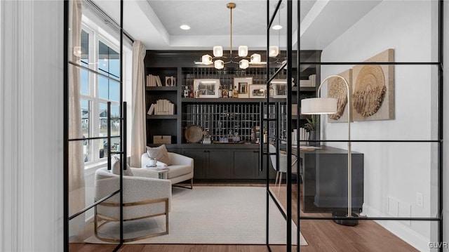 interior space featuring a notable chandelier, hardwood / wood-style floors, and a tray ceiling