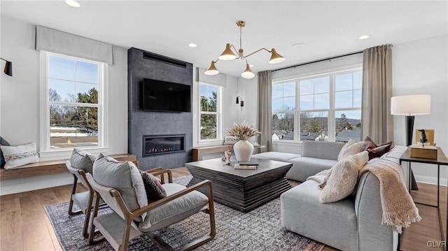 living room with a notable chandelier, hardwood / wood-style floors, a tile fireplace, and a wealth of natural light