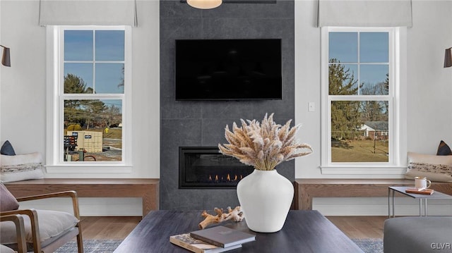 living room with a tiled fireplace and hardwood / wood-style floors