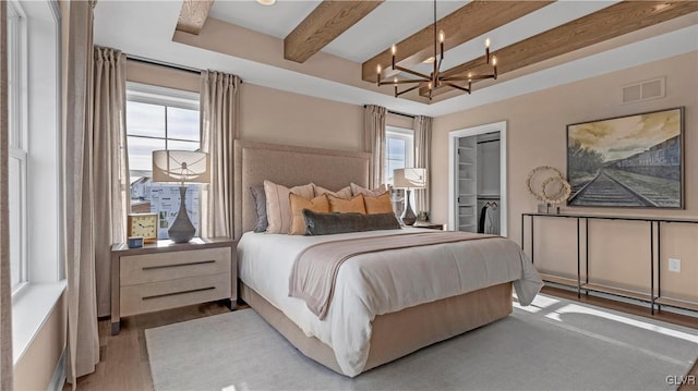 bedroom featuring a spacious closet, a closet, a chandelier, multiple windows, and beam ceiling