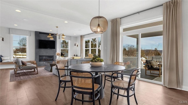 dining space featuring a fireplace, dark wood-type flooring, and a chandelier