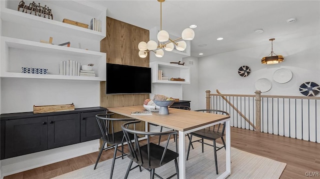 dining space with light wood-type flooring and an inviting chandelier