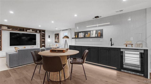 dining area featuring wet bar, wine cooler, and light hardwood / wood-style floors