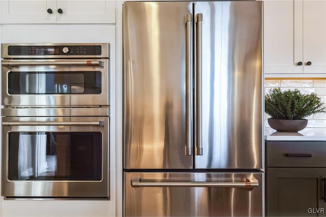 kitchen with appliances with stainless steel finishes, white cabinets, and tasteful backsplash