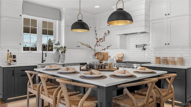 kitchen featuring sink, decorative backsplash, white cabinetry, and pendant lighting