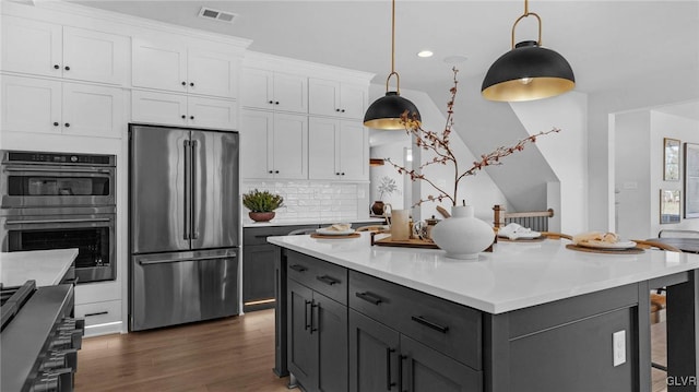 kitchen with appliances with stainless steel finishes, hanging light fixtures, gray cabinetry, white cabinetry, and tasteful backsplash