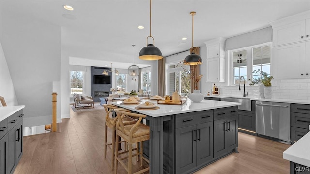 kitchen with dishwasher, a kitchen island, decorative backsplash, white cabinets, and sink