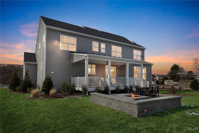 back house at dusk featuring a patio, a fire pit, covered porch, and a yard