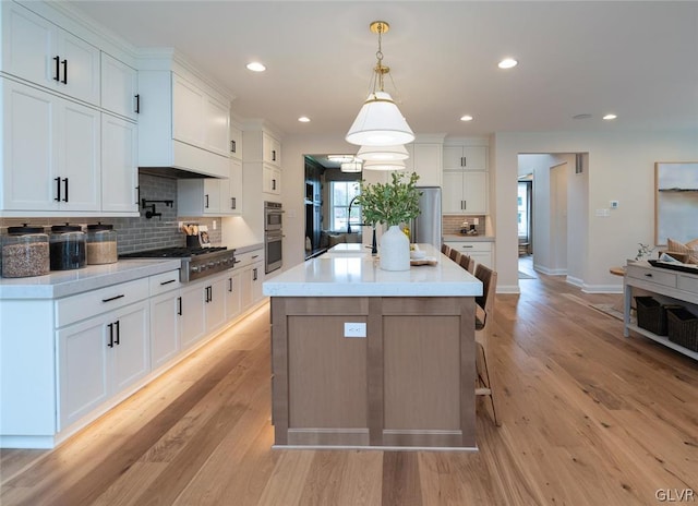 kitchen with white cabinetry, tasteful backsplash, light hardwood / wood-style flooring, and appliances with stainless steel finishes