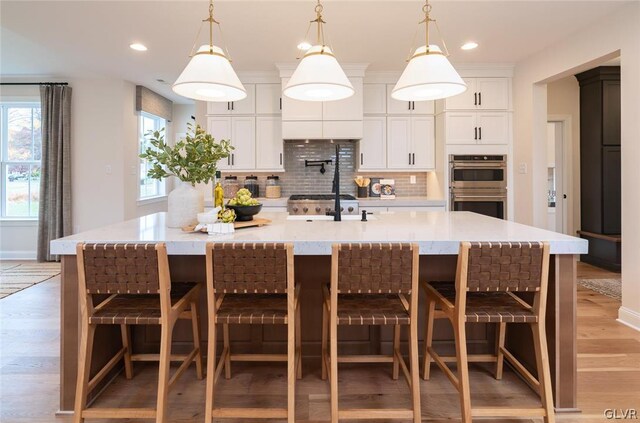 kitchen with backsplash, a breakfast bar, a spacious island, and stainless steel double oven