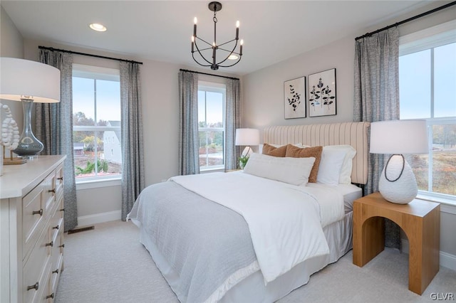 carpeted bedroom featuring an inviting chandelier and multiple windows