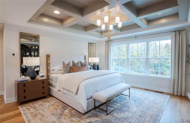 bedroom featuring an inviting chandelier, beamed ceiling, light hardwood / wood-style flooring, and coffered ceiling