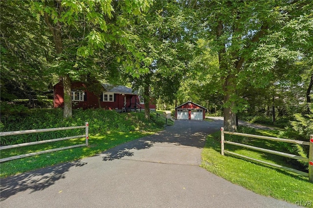 view of front facade with a detached garage, fence, and an outbuilding