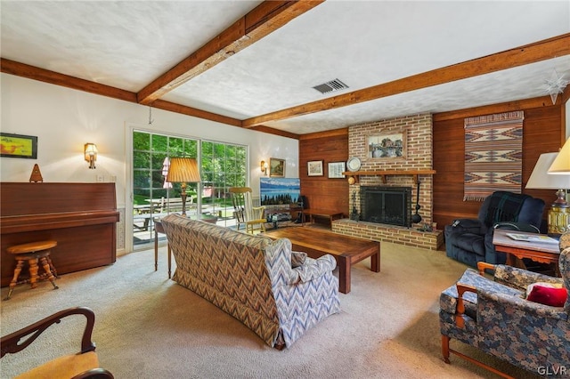 living room featuring light carpet, wooden walls, visible vents, beamed ceiling, and a fireplace