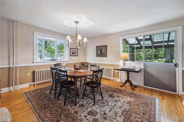 dining area with radiator, a notable chandelier, baseboards, and wood finished floors