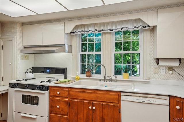 kitchen with white appliances, light countertops, a sink, and wall chimney exhaust hood