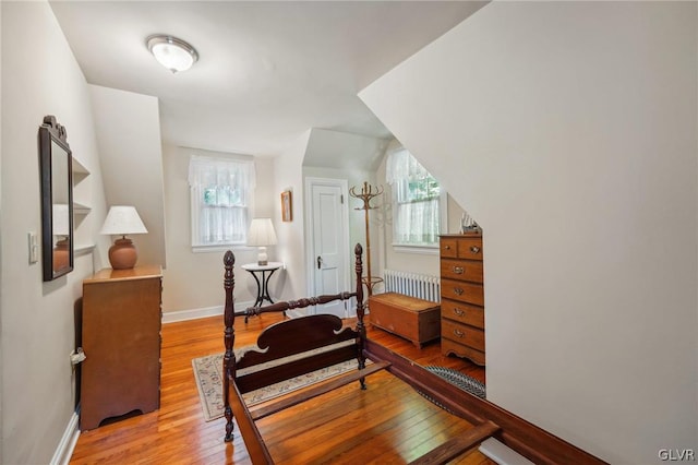 bedroom featuring baseboards, light wood-style flooring, and radiator heating unit