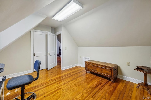 office space featuring lofted ceiling, baseboards, and light wood finished floors