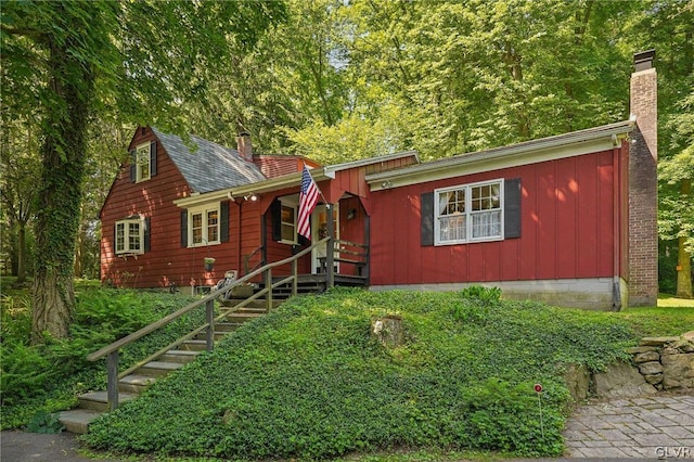 view of front of house featuring stairway, roof with shingles, and a chimney