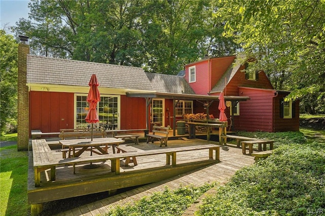 rear view of house featuring a chimney and a wooden deck