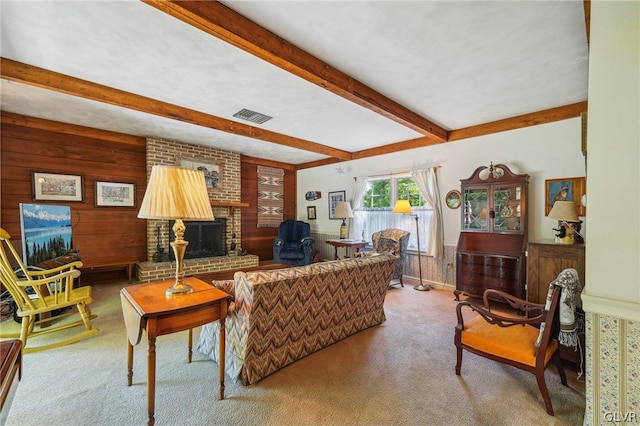 living area with a brick fireplace, wooden walls, beam ceiling, and carpet flooring