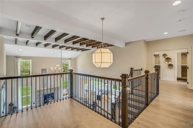 hallway with beamed ceiling, a chandelier, and light hardwood / wood-style floors